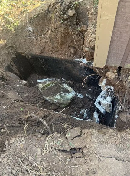 A broken piece of glass is lying in a hole in the ground.