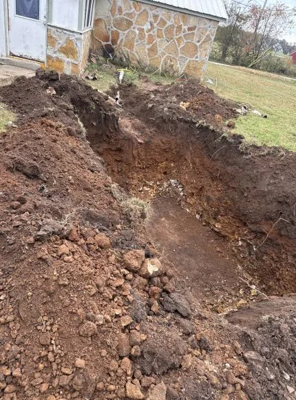 A large hole dug in the ground, with dirt piled up around it.