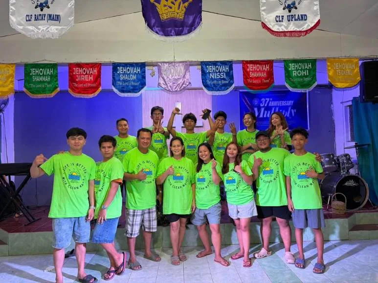 A group of people wearing green shirts and shorts standing on stage, posing for a photo.