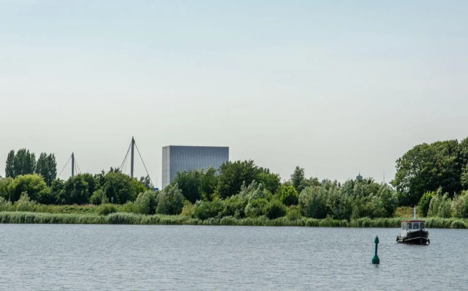 A serene industrial landscape featuring a water tower and a boat on a tranquil body of water.