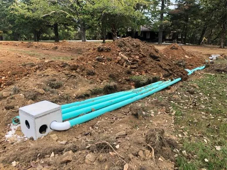 A construction site featuring blue pipes and white boxes in a natural setting.